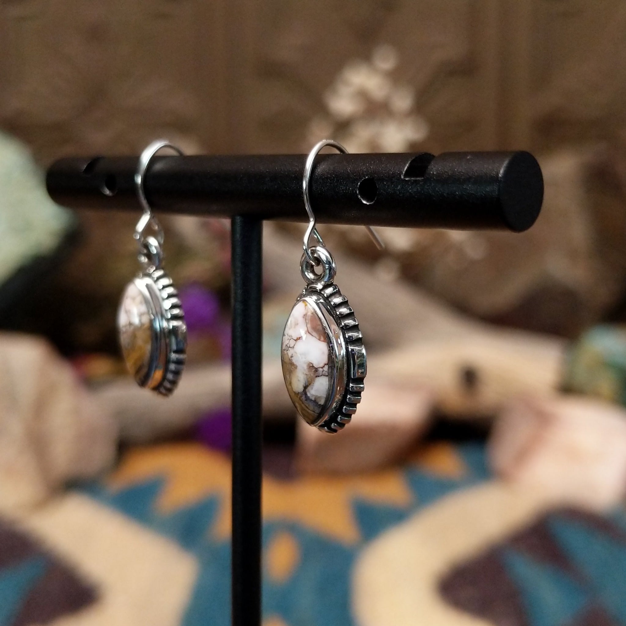 Handcrafted sterling silver navette earrings featuring natural Wild Horse stone with creamy white and rich brown patterns, accented by detailed silver beadwork and French hook ear wires; side view.
