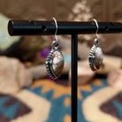 Handcrafted sterling silver navette earrings featuring natural Wild Horse stone with creamy white and rich brown patterns, accented by detailed silver beadwork and French hook ear wires; side view.