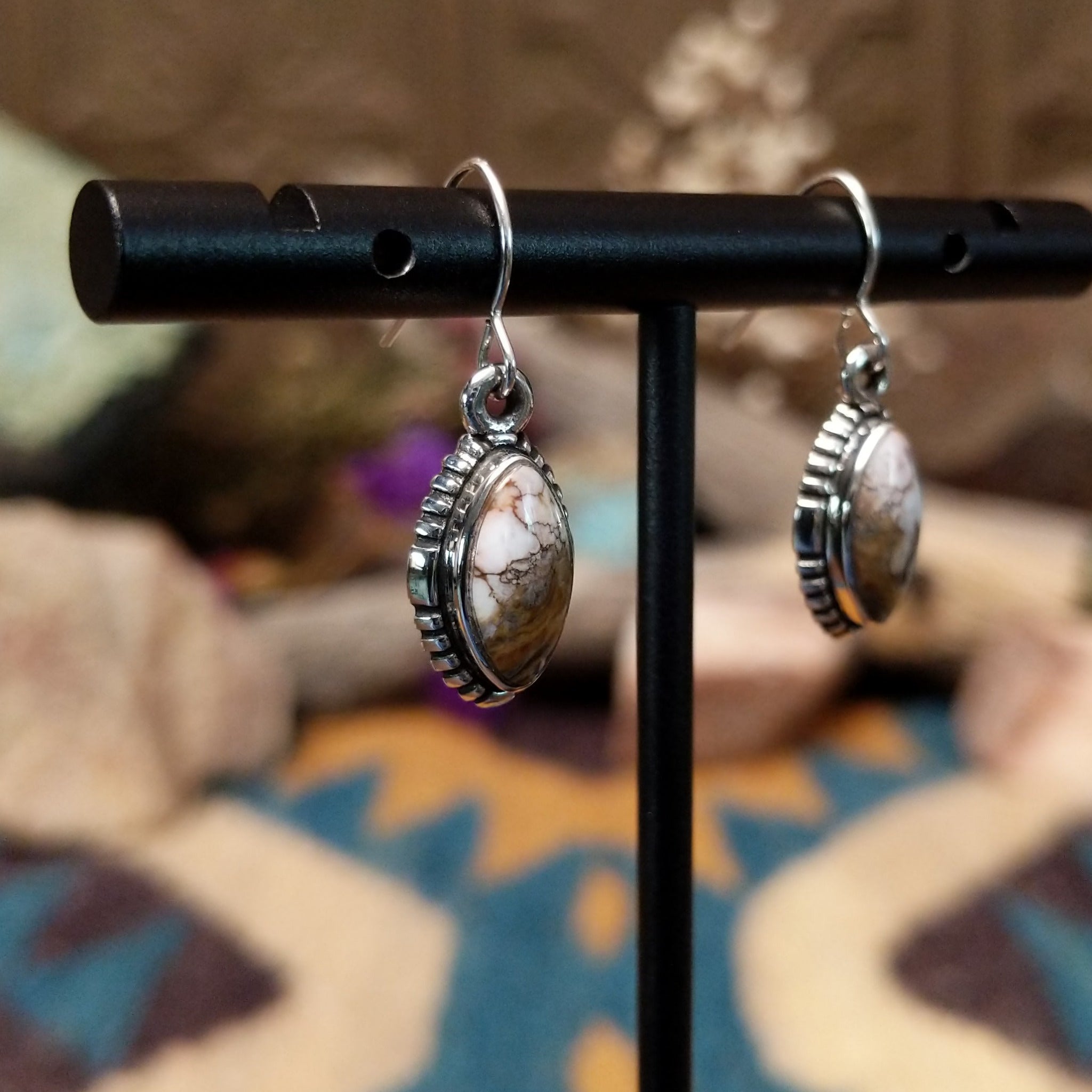 Handcrafted sterling silver navette earrings featuring natural Wild Horse stone with creamy white and rich brown patterns, accented by detailed silver beadwork and French hook ear wires; side view.
