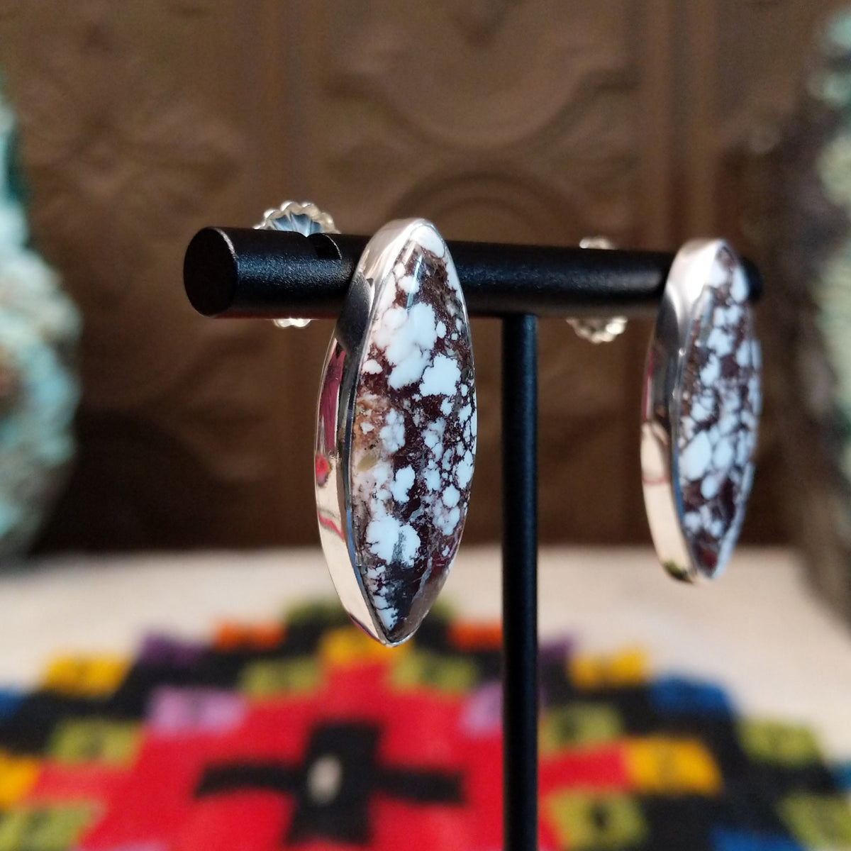 Wild Horse Earrings by Diane Wylie featuring elongated navette-shaped stones with white and reddish-brown matrix patterns set in smooth silver bezels; side view.