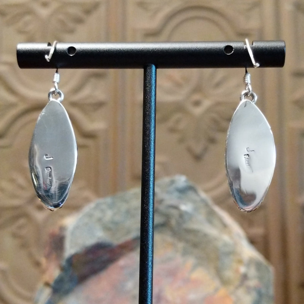 The polished sterling silver backing and artist's stamp.