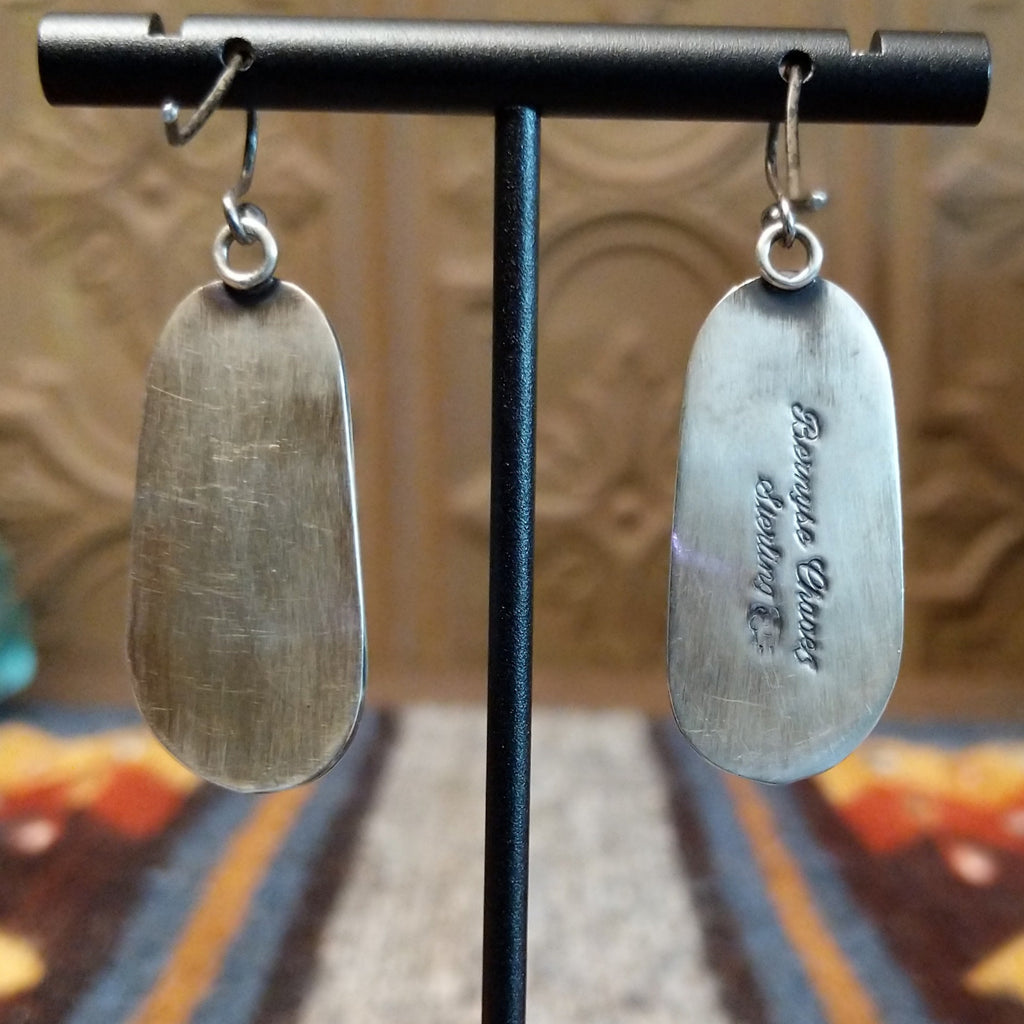 The back of the sterling silver pendant that features the artist's signature and authentication stamp.