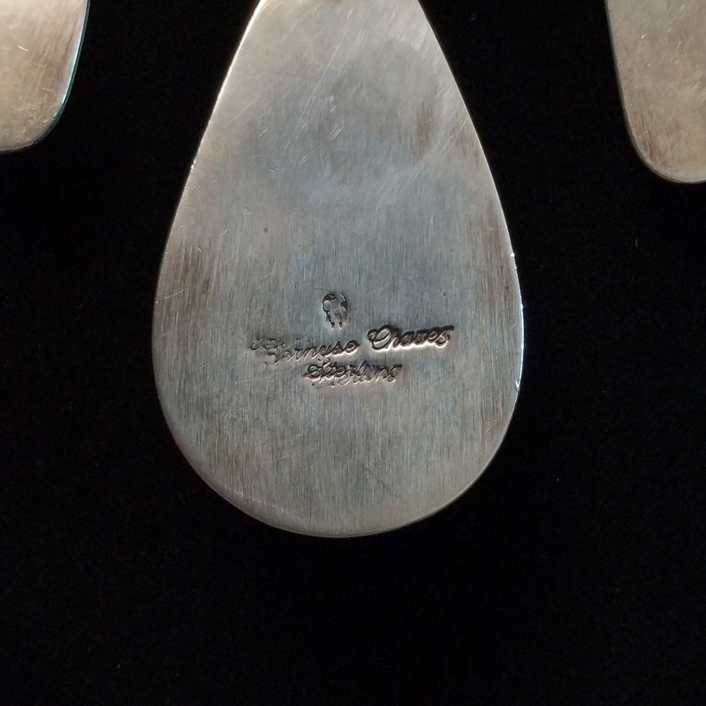 A close-up of the signature and authentication on the back of the necklace's center pendant.