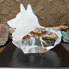 A frosted Lucite sculpture shaped like a wolf's head with a hand-painted wolf running inside the clear crystal interior, creating the illusion of movement.