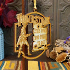 A laser-cut wooden hanging ornament featuring a cowboy silhouette and the words  “The Town Too Tough to Die,” displayed against a rustic decorative background.