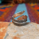 Wrapped silver feather ring by Lena Platero with detailed linework and overlapping design.