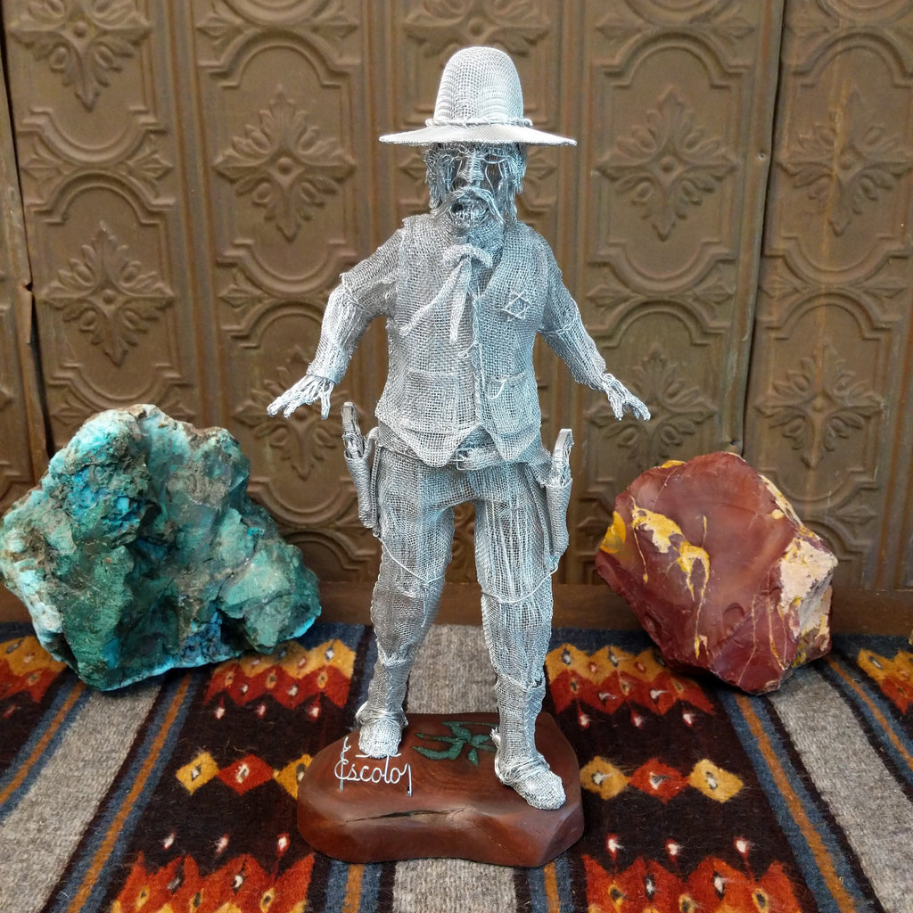 Wire sculpture of Wyatt Earp showing a silver wire figure in a hat, vest, and holsters with arms outstretched.