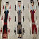 Yei Navajo rug by Milicent Platero featuring three traditional Yei figures on a natural gray background with geometric accents and a striped side border.