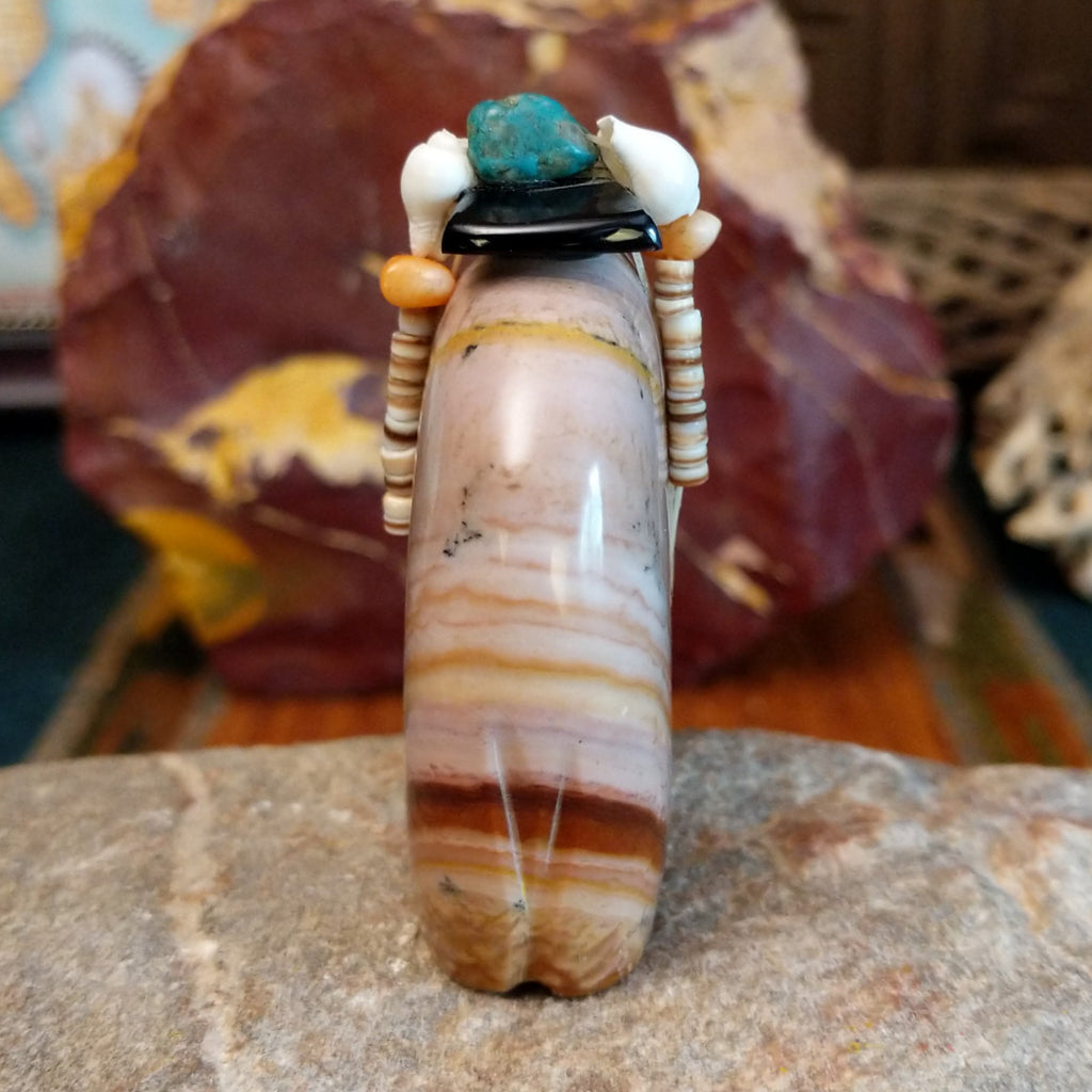Banded dolomite carved into a bear with turquoise arrows inlaid on the body and pen shell and various stones beaded along its' torso.
