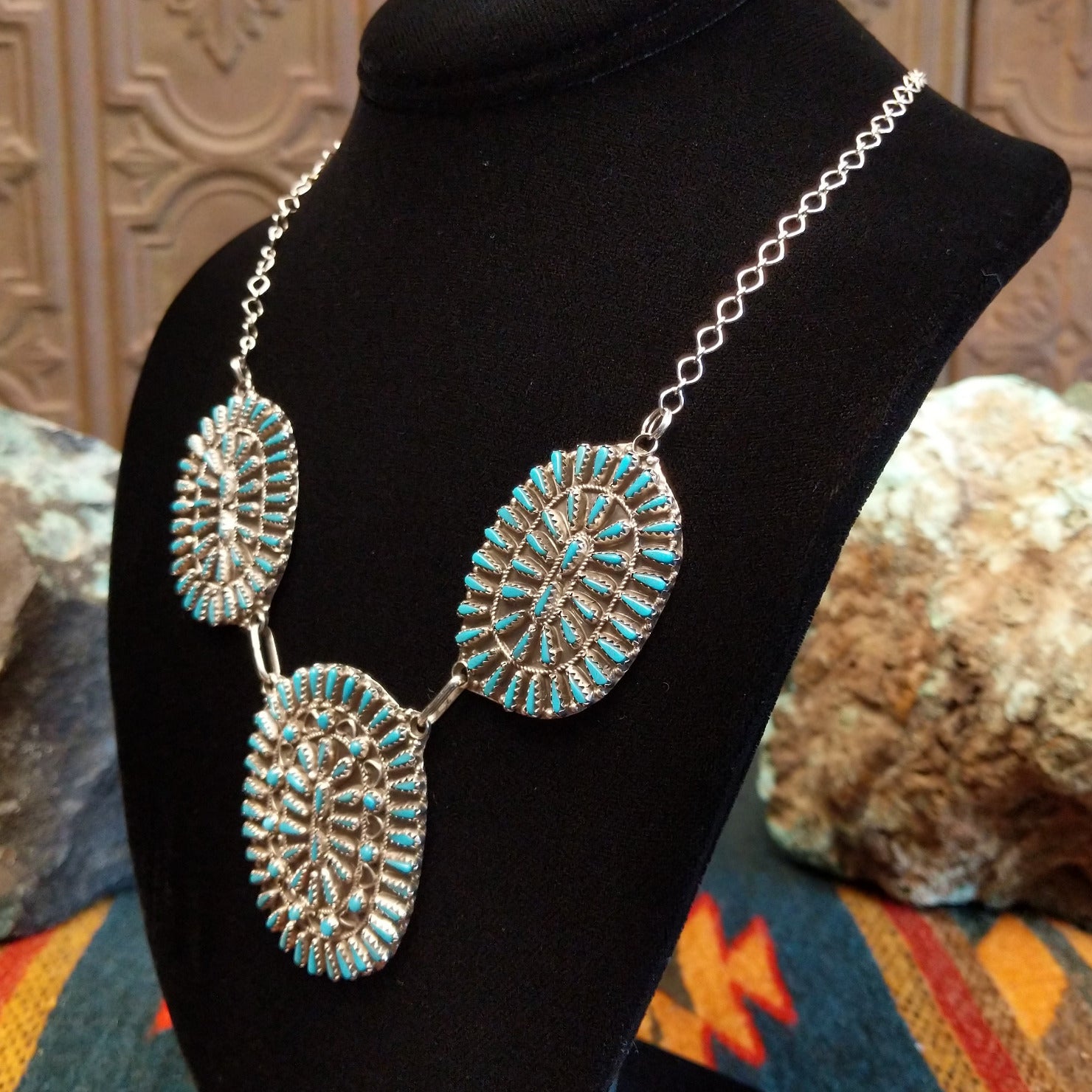 Sterling silver necklace with needlepoint clusters set on three conchos, and the turquoise set in notched bezels.