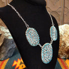 Sterling silver necklace with needlepoint clusters set on three conchos, and the turquoise set in notched bezels.