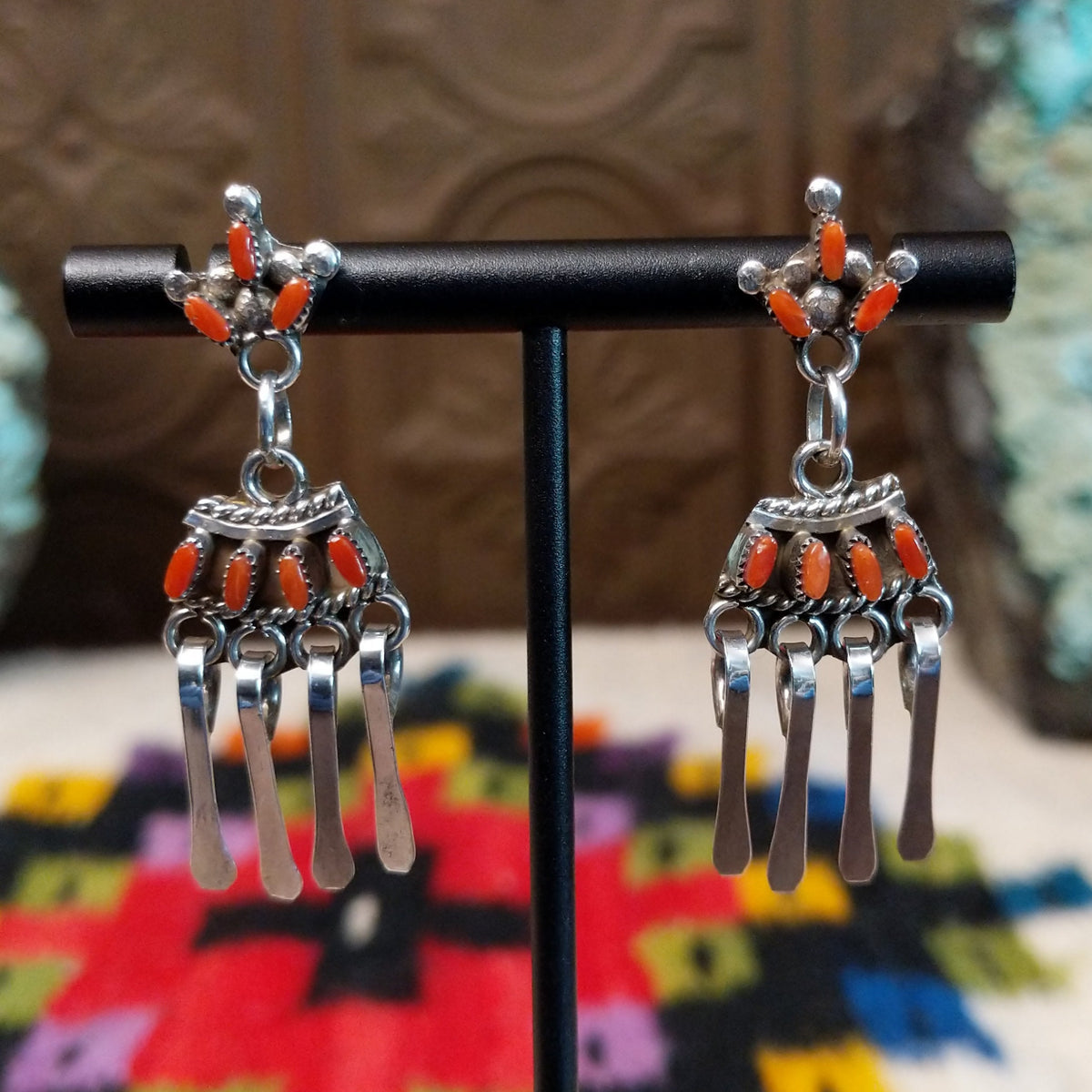 Zuni Coral Earrings featuring red-orange coral stones in detailed silver settings with clustered accents and multiple long dangling silver elements.