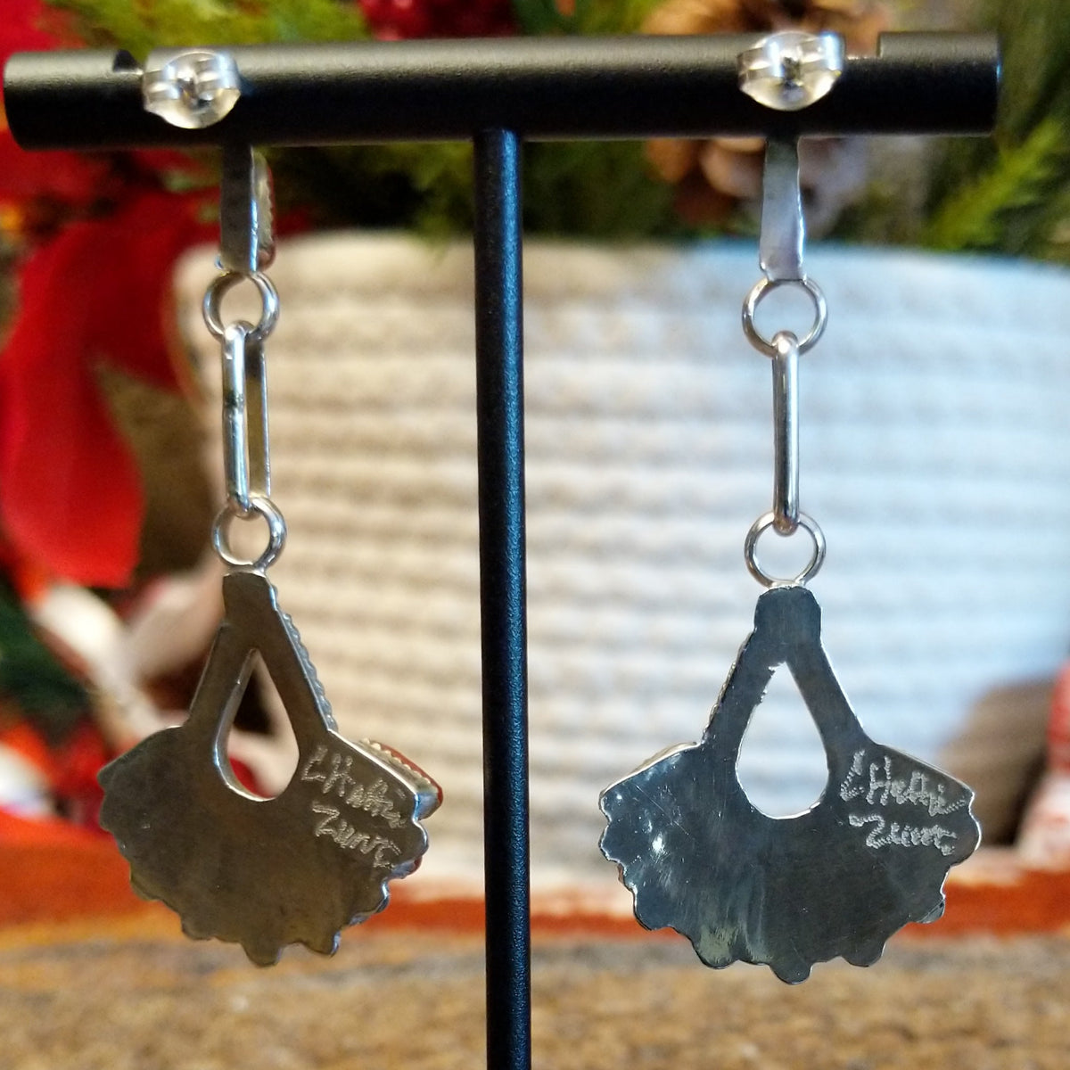 The back of the earrings feature the artisan's stamped signature.