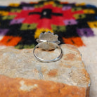 This vibrant Zuni Coral Flower Ring features teardrop-shaped red coral stones arranged as flower petals around a raised silver center, accented with rounded silver details; underside view.