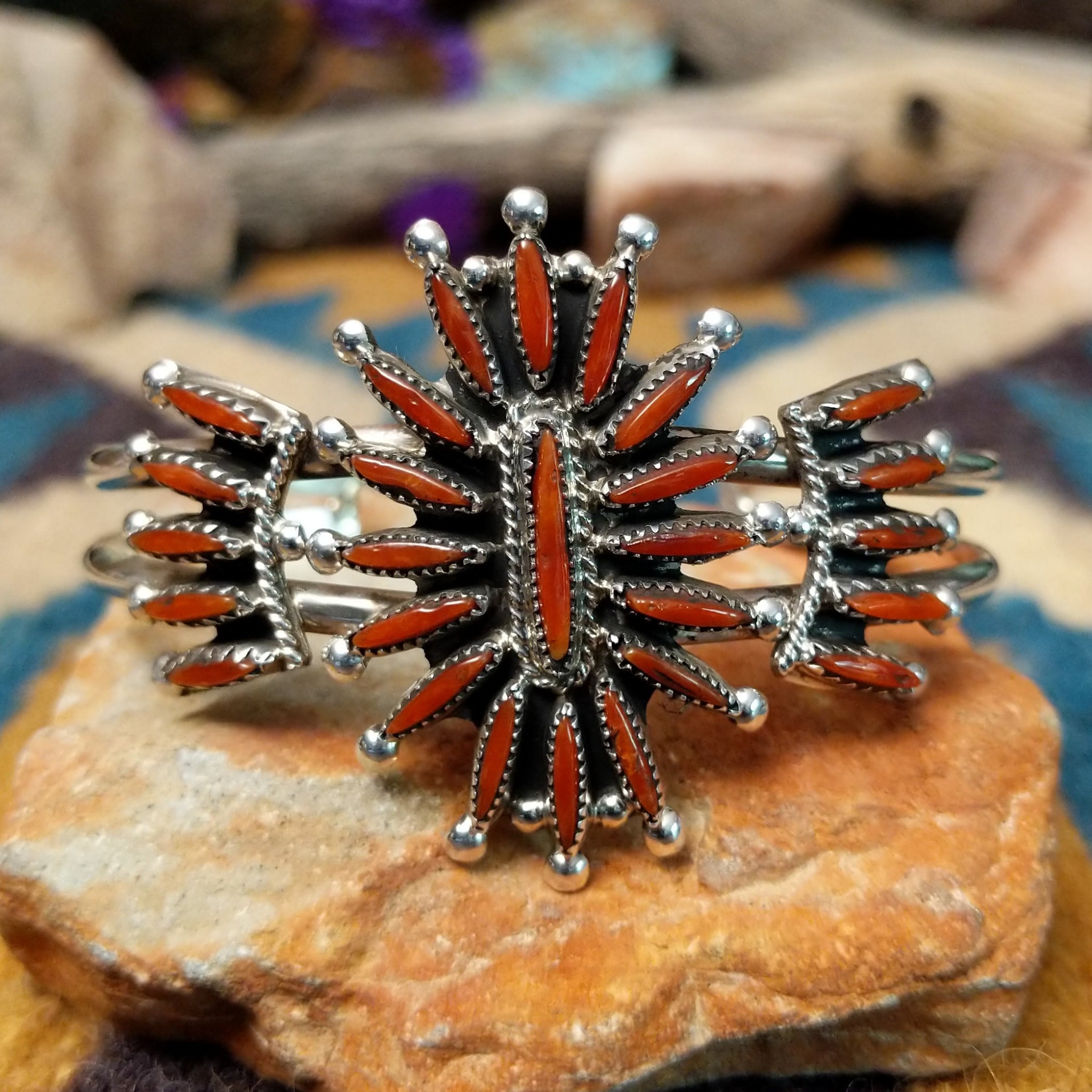 Handcrafted Zuni sterling silver cuff by G.E. featuring coral needlepoint stones in a traditional concho design with silver bead accents and a triple-shank cuff.