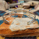 Handcrafted Zuni sterling silver cuff by G.E. featuring coral needlepoint stones in a traditional concho design with silver bead accents and a triple-shank cuff; underside view.