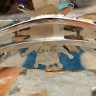 Handcrafted Zuni sterling silver cuff by G.E. featuring coral needlepoint stones in a traditional concho design with silver bead accents and a triple-shank cuff; artisan signature.