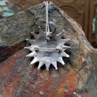 Zuni coral pendant and pin featuring red-orange teardrop-shaped coral stones arranged in a circular sunburst cluster with twisted silver detailing; Sterling silver stamp.