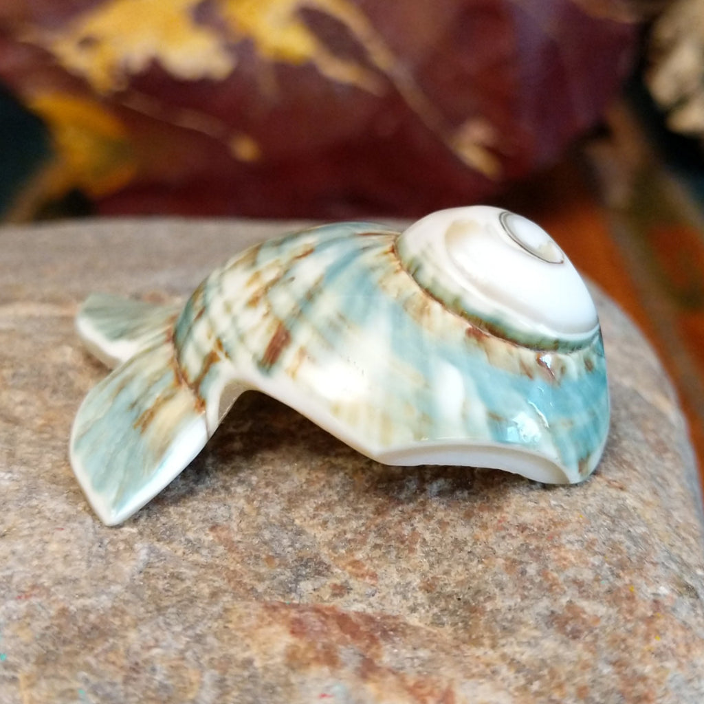 Green snail shell carved into a fish with intricate matrix along the shell.