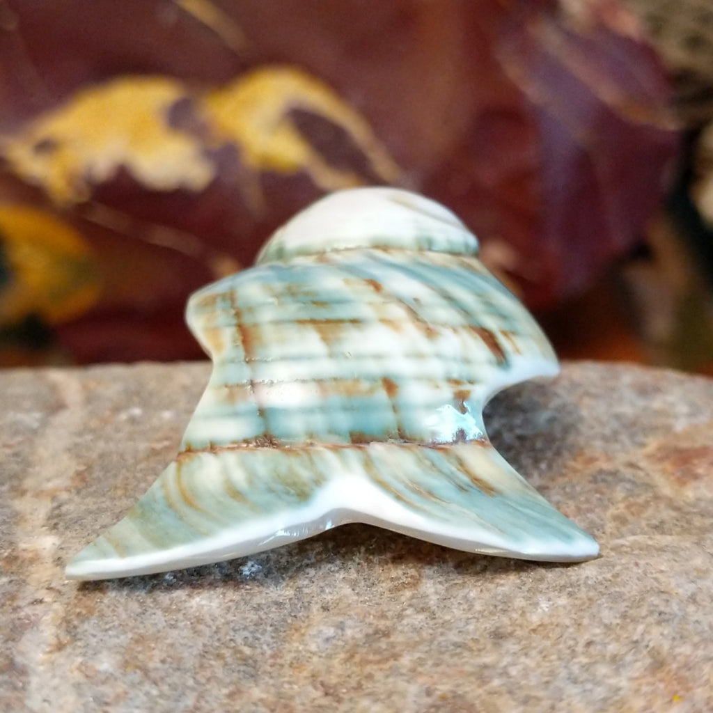Green snail shell carved into a fish with intricate matrix along the shell.
