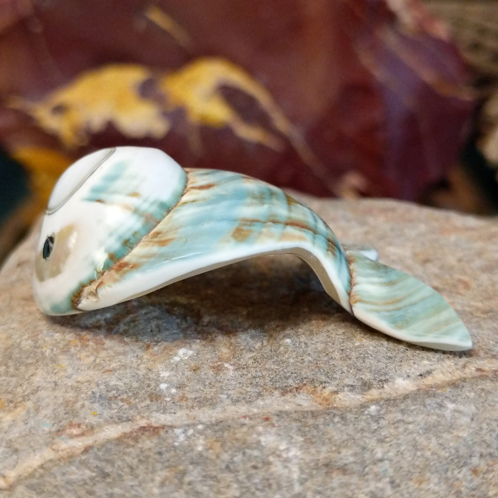 Green snail shell carved into a fish with intricate matrix along the shell.