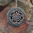 Zuni needlepoint turquoise pendant and pin by Vincent Johnson featuring slender turquoise stones arranged around a circular silver frame with intricate twisted-wire floral details and silver accents.