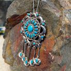 Zuni turquoise dangle pendant and pin by Lorraine Waatsa featuring a floral turquoise cluster, polished silver loops, twisted-wire detailing, and five turquoise-accented dangles; side view.