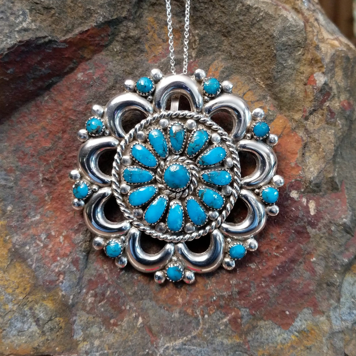 Zuni turquoise pendant and pin by Lorraine Waatsa featuring a floral cluster of turquoise stones surrounded by polished silver loops, twisted wire, and silver bead detailing.