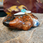 Brown and black matrix stone carved into a frog fetish with turquoise and mother of pearl tied to its' back.