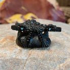 Three black onyx carved horned toad fetishes on a rock.
