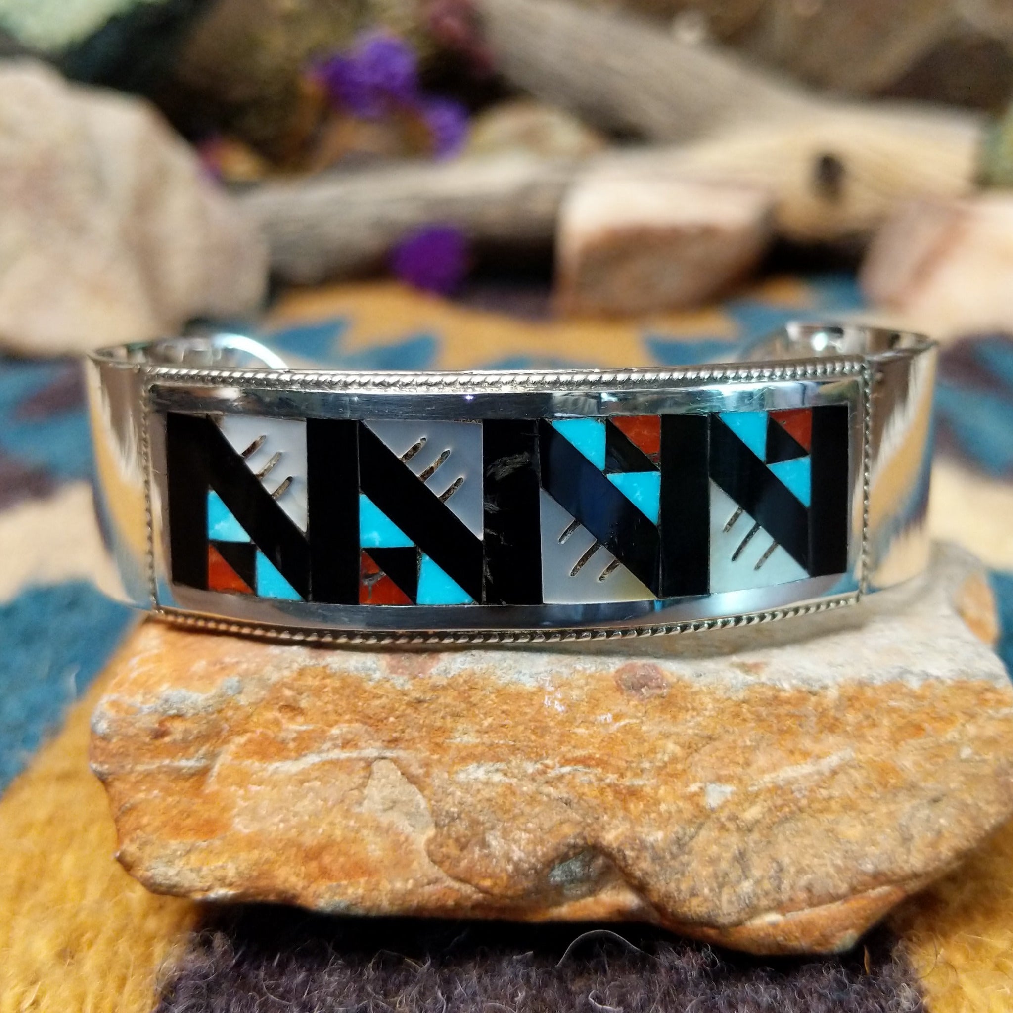 Handcrafted sterling silver Zuni cuff by Leander & Lisa Othole featuring a bold geometric channel inlay design with a polished sterling silver cuff and traditional Southwestern craftsmanship.