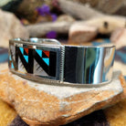 Handcrafted sterling silver Zuni cuff by Leander & Lisa Othole featuring a bold geometric channel inlay design with a polished sterling silver cuff and traditional Southwestern craftsmanship; side view.