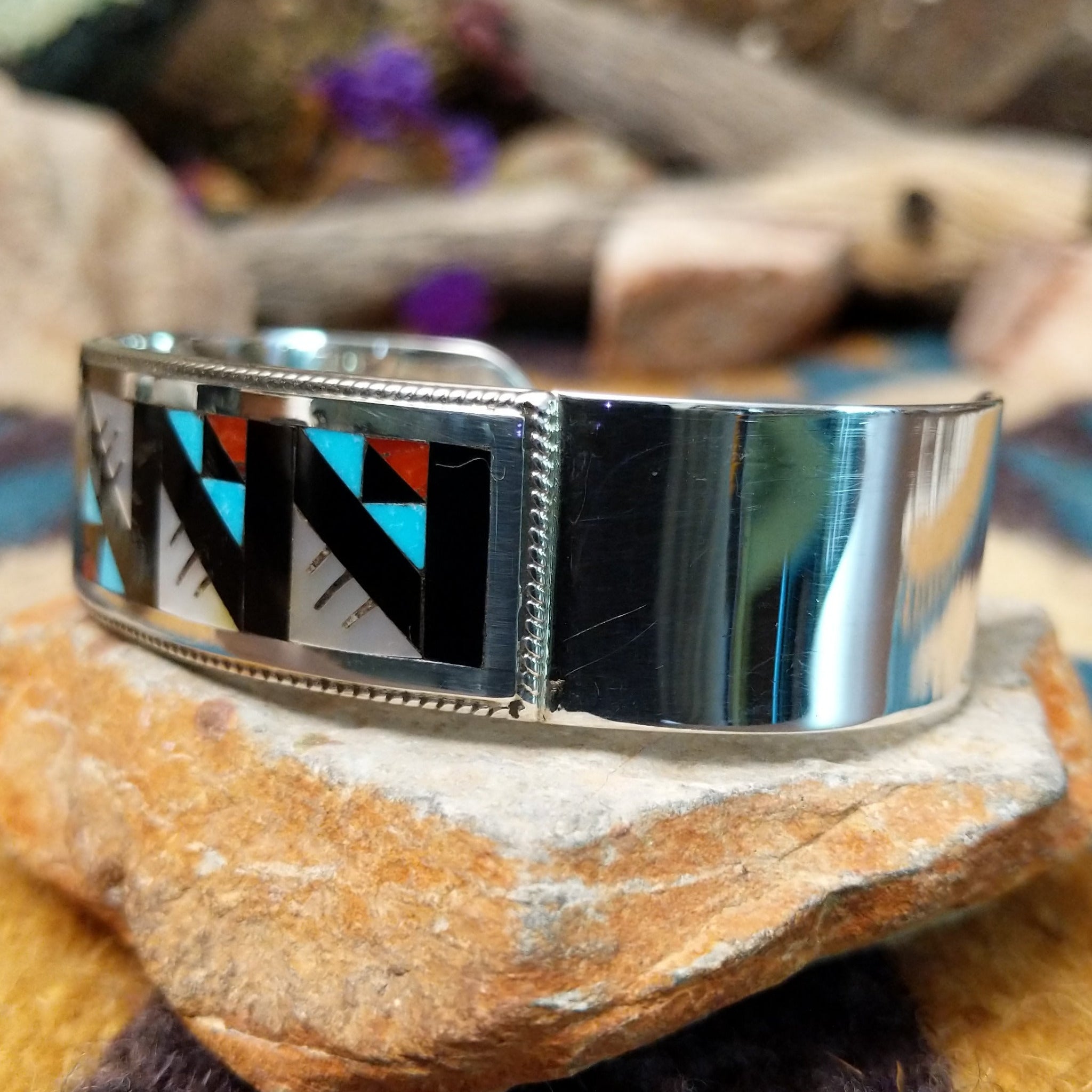 Handcrafted sterling silver Zuni cuff by Leander & Lisa Othole featuring a bold geometric channel inlay design with a polished sterling silver cuff and traditional Southwestern craftsmanship; side view.