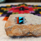 This colorful Zuni Inlay Ring features rectangular turquoise, black, and reddish-orange stone inlay in a geometric pattern, framed in silver with beaded accents along the sides.