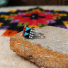 This colorful Zuni Inlay Ring features rectangular turquoise, black, and reddish-orange stone inlay in a geometric pattern, framed in silver with beaded accents along the sides; side view.