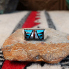 Zuni inlay ring by S.B. featuring a rectangular geometric design in turquoise, black onyx, coral, and mother of pearl inlay set in a polished silver band.