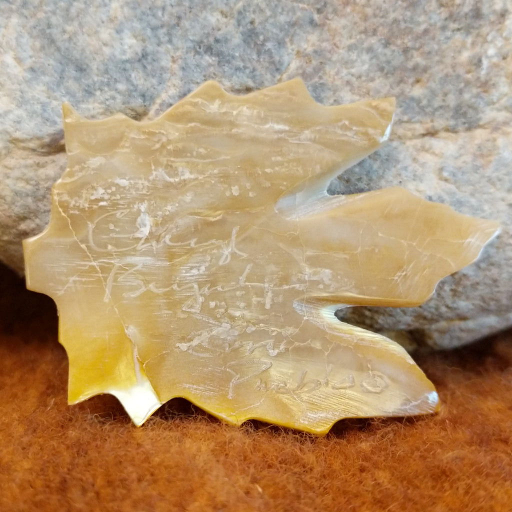 The artisan's signature is found on the bottom of the leaf.