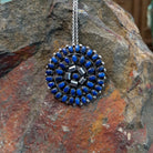 Zuni lapis cluster pendant and pin by Lorraine Waatsa featuring deep blue lapis stones arranged in concentric circles with twisted and sculptural silver detailing.
