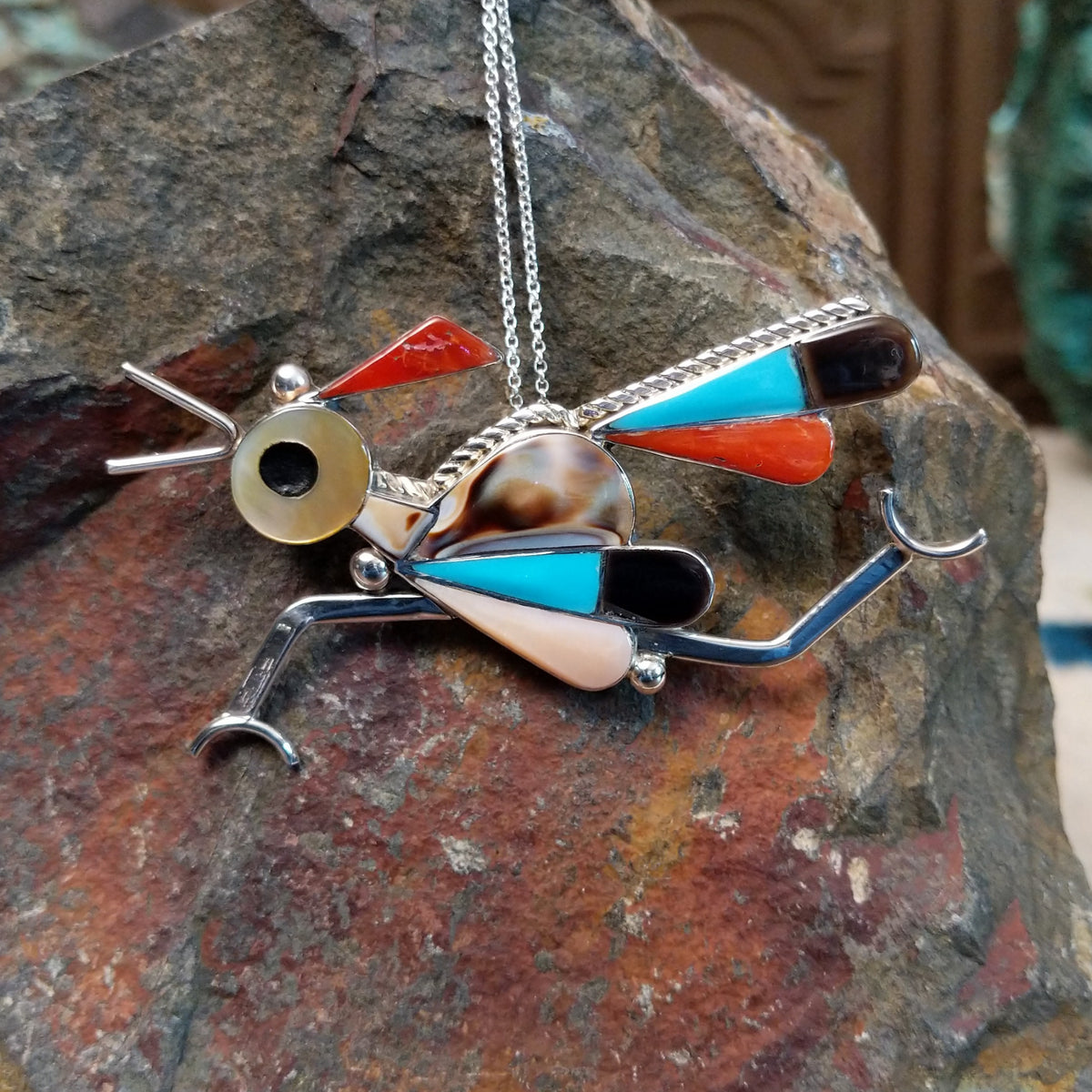 Large Zuni roadrunner pendant and pin by K.E. featuring turquoise, red-orange, black, cream, and patterned shell inlay with sculpted silver legs, beak, wings, and tail.