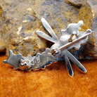 The underside of the pendant showcases the artisan's stamped signature and pin closure.