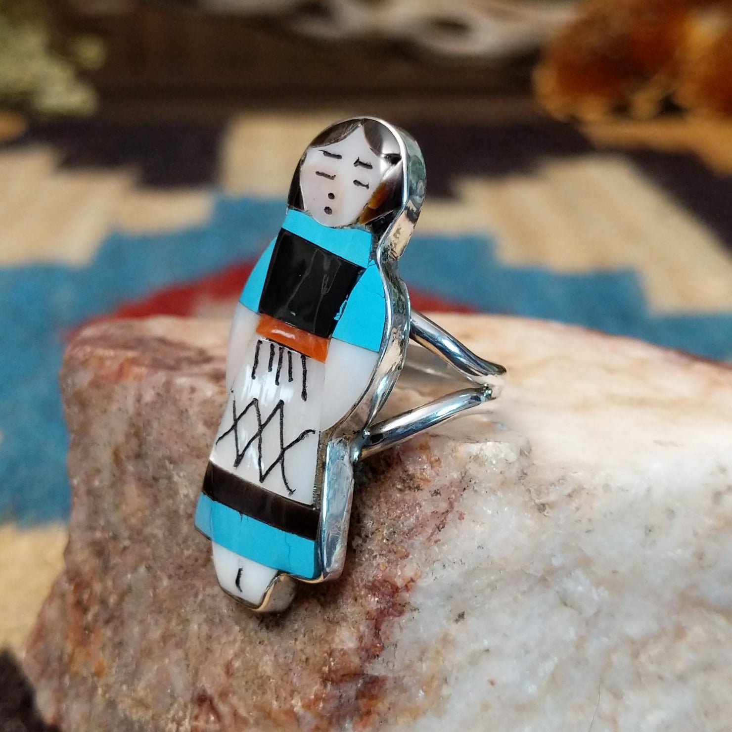 Sterling silver ring with maiden motif featuring turquoise, black onyx, coral, and mother of pearl.
