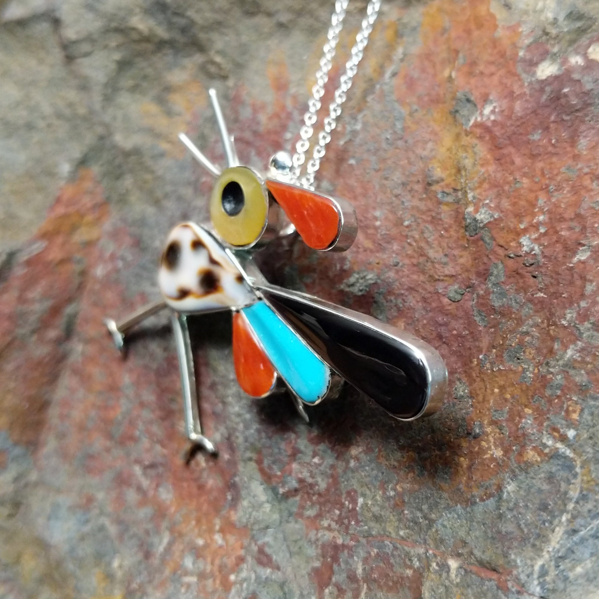 Handcrafted sterling silver multistone roadrunner pin and pendant by K.E., featuring traditional Zuni stone inlay in a colorful bird design; side view.