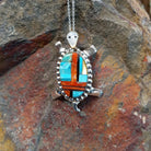 Zuni multistone turtle pendant and pin by W.J.H. featuring colorful turquoise, red-orange, black, and cream inlay set in a detailed silver turtle design.