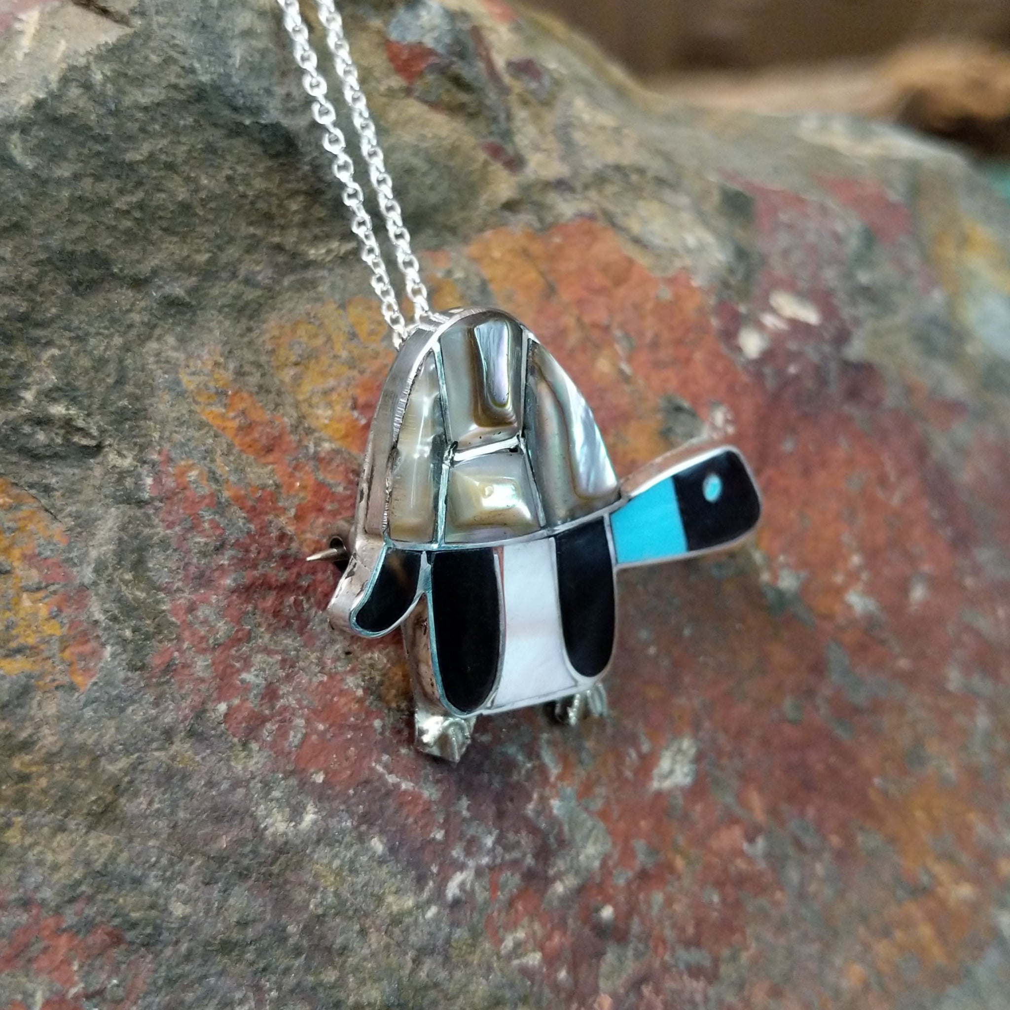 Handcrafted sterling silver multistone turtle pin and pendant by Lorretta, featuring traditional Zuni stone inlay in a turtle design; side view.