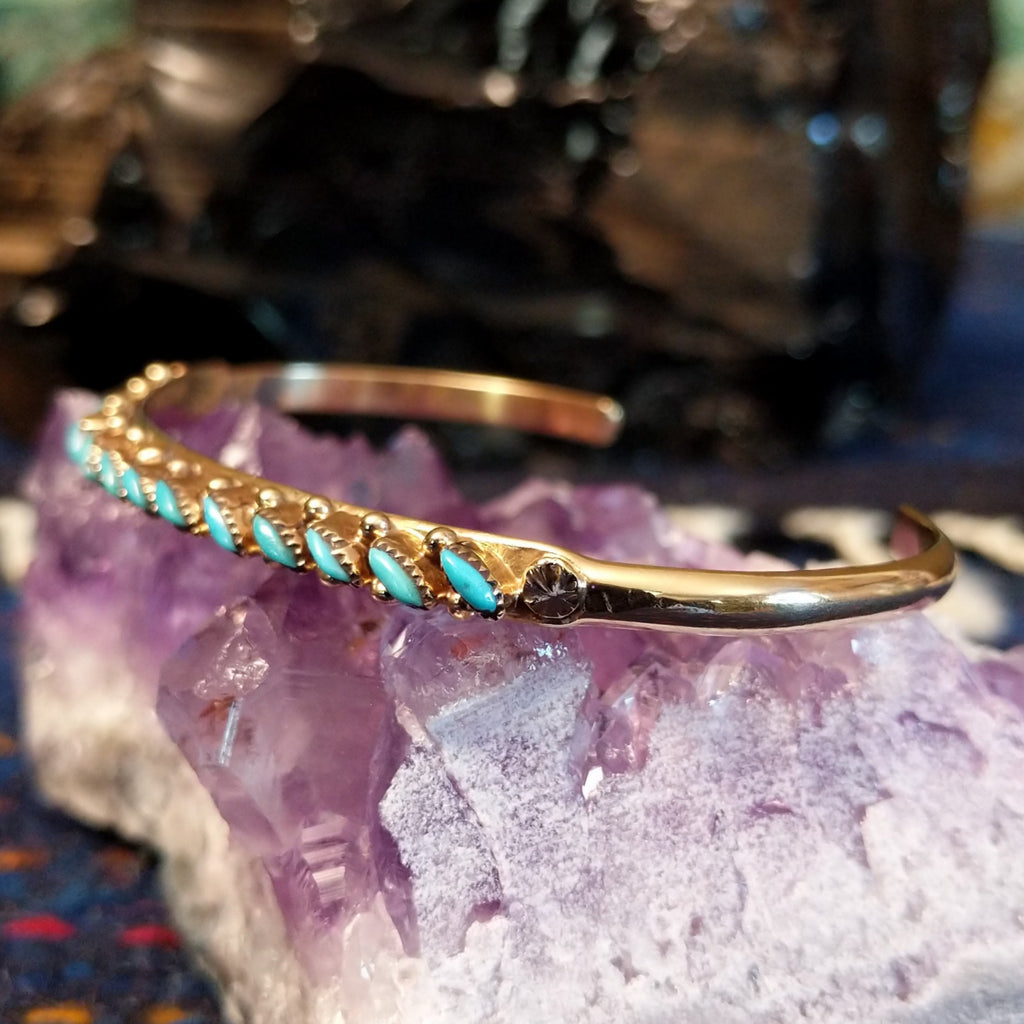 Zuni needlepoint turquoise cuff featuring the intricate design and gold beading.