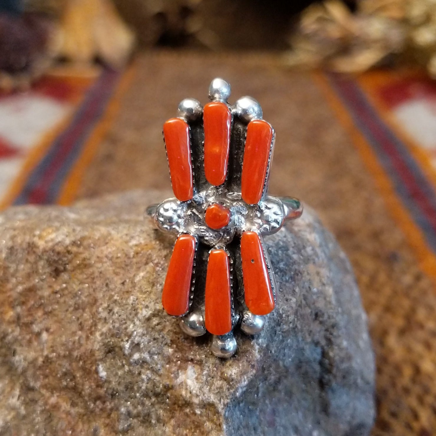 Sterling silver ring with coral set in seven bezels, featuring dot work and a thin band.