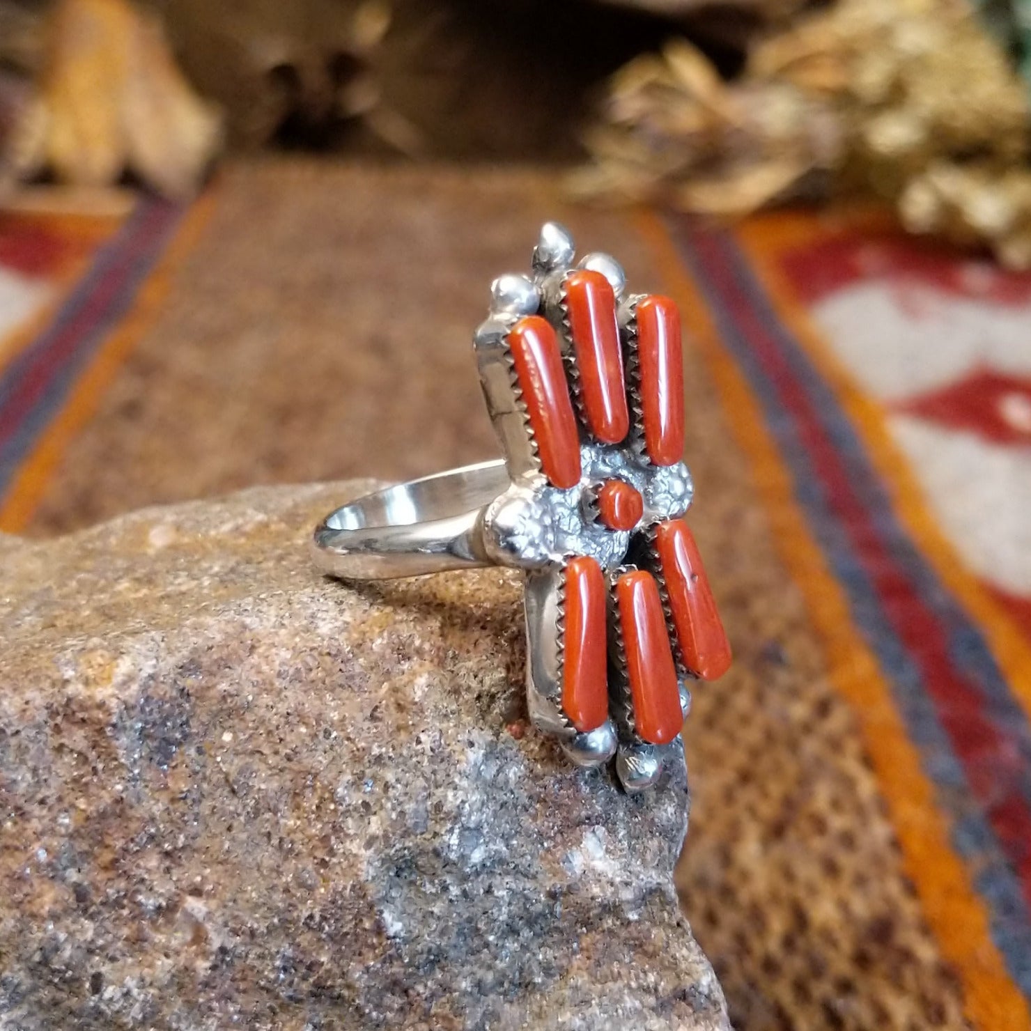 Sterling silver ring with coral set in seven bezels, featuring dot work and a thin band.