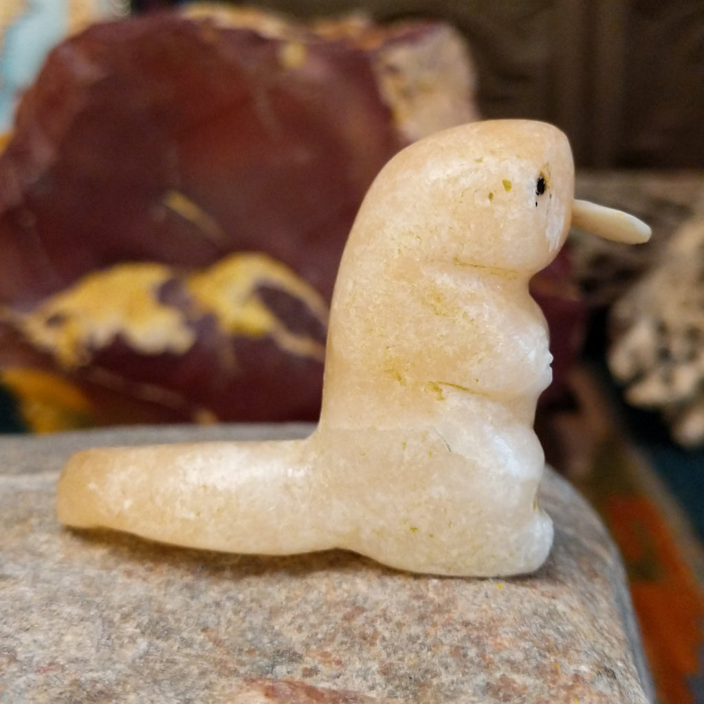 Light orange alabaster carved into an otter holding a fish in it's mouth and painted, black eyes.