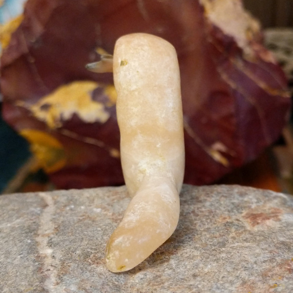 Light orange alabaster carved into an otter holding a fish in it's mouth and painted, black eyes.