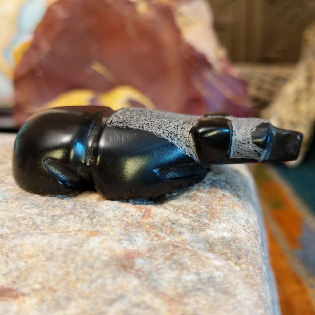 Black marble carved in the shape of a panda laying down.